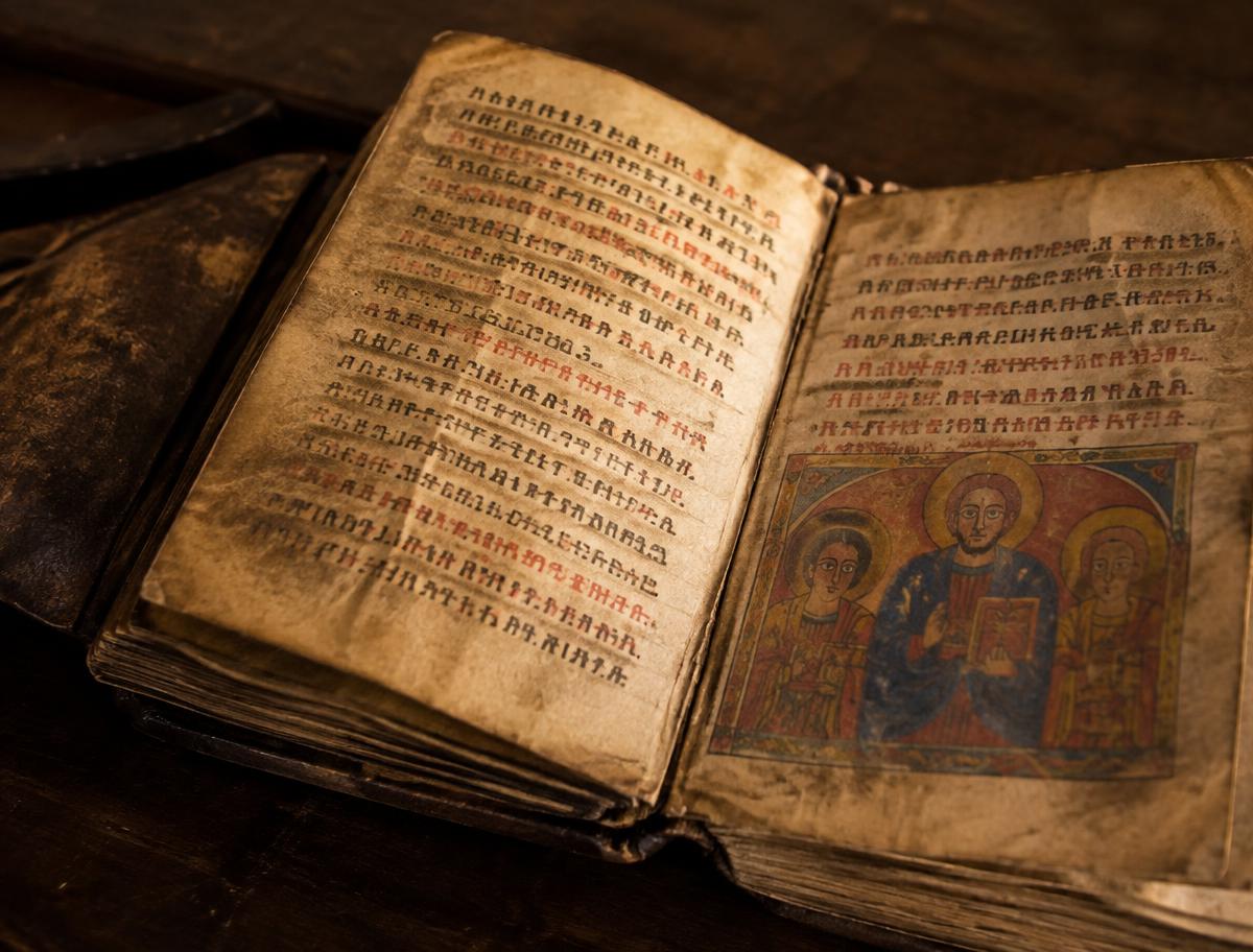 An open handwritten parchment manuscript in Geʽez script with a small illumination